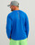 HUK Pursuit LS Crew, man wearing a blue long-sleeve fishing shirt and a grey cap, with the text 'HUK FISHING' printed on the back and sleeve.