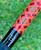 Nick's Custom Rods 2025 Fall Nick's Custom Rods - CTS 1205 Spinning fishing rod with vibrant geometric patterned design in orange, pink, and black colors, against a blurred green background.
