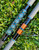 Nick's Custom Rods 2025 Fall Nick's Custom Rods - CTS 1205 Spinning fishing rod with intricate geometric design in blue, black, and copper colors lying on green grass.