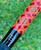 NICK'S CUSTOM RODS 2025 Fall Nick's Custom Rods - CTS 1205 Spinning, close-up of a brightly colored fishing rod with a geometric orange, pink, purple, and black pattern against a blurred green background.