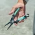 TOADFISH Toadfish Inshore 8" Stainless Pliers - Elite Series, hand holding the fishing pliers outdoors