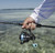 Toadfish Carbon II Spinning Combos, a person holding a fishing rod and spinning reel over a body of water.