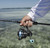 Toadfish Carbon II Spinning Combos, fishing rod and reel in hand by the water.