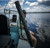 TOADFISH Toadfish Elite Stowaway Travel Rod, person holding the fishing rod on a boat with a water body in the background.