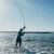 TOADFISH Toadfish Surf Combo, a person fishing in the ocean with a fishing rod and reel