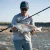 TOADFISH Toadfish Surf Combo, person holding a large fish while standing in shallow water on a beach.