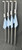 DEERFIELD FABRICATION Deerfield Open Face 2.0 Sand Spike, four steel sand spikes with blue towels hanging from hooks, set against a dark background.