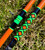 Nick's Custom Rods 2026 Nick's Custom Rods - CTS 1205 Conventional fishing rod, brightly colored with orange, black, green, and geometric patterns, lying on grass.