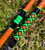 Nick's Custom Rods 2026 Nick's Custom Rods - CTS 1205 Conventional fishing rod, colorful with orange, green, and black geometric patterns lying on grass.