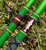 Nick's Custom Rods 2026 Nick's Custom Rods - CTS 1205 Conventional fishing rod, green and maroon color with fish artwork, lying on grass.