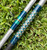 Nick's Custom Rods 2026 Nick's Custom Rods - CTS 1205 Conventional fishing rod, with a colorful geometric pattern and metallic finish, resting on green grass.