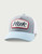 HUK Youth Script Trucker, light blue and white baseball cap with a gray front panel and red and black embroidered logo patch.