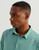 HUK Pursuit Polo, a man wearing a light green polo shirt made of comfortable, breathable fabric.
