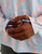 HUK Icon Printed Crew, close-up of a person wearing a light blue and peach patterned long sleeve shirt with the HUK logo on the wrist band.