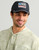 HUK Born Wave Performance Hat, black cap with a curved bill and embroidered patch logo on front.