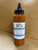 JJ's Truffle Hot Sauce, a squeeze bottle of flavorful hot sauce with a black nozzle cap on a wooden surface.