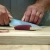 ToADFISH Toadfish 8-inch Abalone Chef Knife, person slicing a piece of raw fish on a wooden cutting board.
