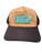 F&F Otto 83-1212 Rubber Patch Hat, stylish trucker cap with a cork-textured front panel and a black brim featuring a green-bordered patch with fishing-themed logo and text.