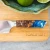 TOADFISH Toadfish Burl Wood Chef Knife Set, detailed view of the knife with a handle made of burl wood and blue resin, resting on a wooden cutting board engraved with the brand name 'TOADFISH'.