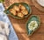 TOADFISH Toadfish Oyster Dishes - 2 Pack, ceramic oyster dishes with a green glaze, one filled with toasted baguette slices and the other with creamy dip on a wooden table.