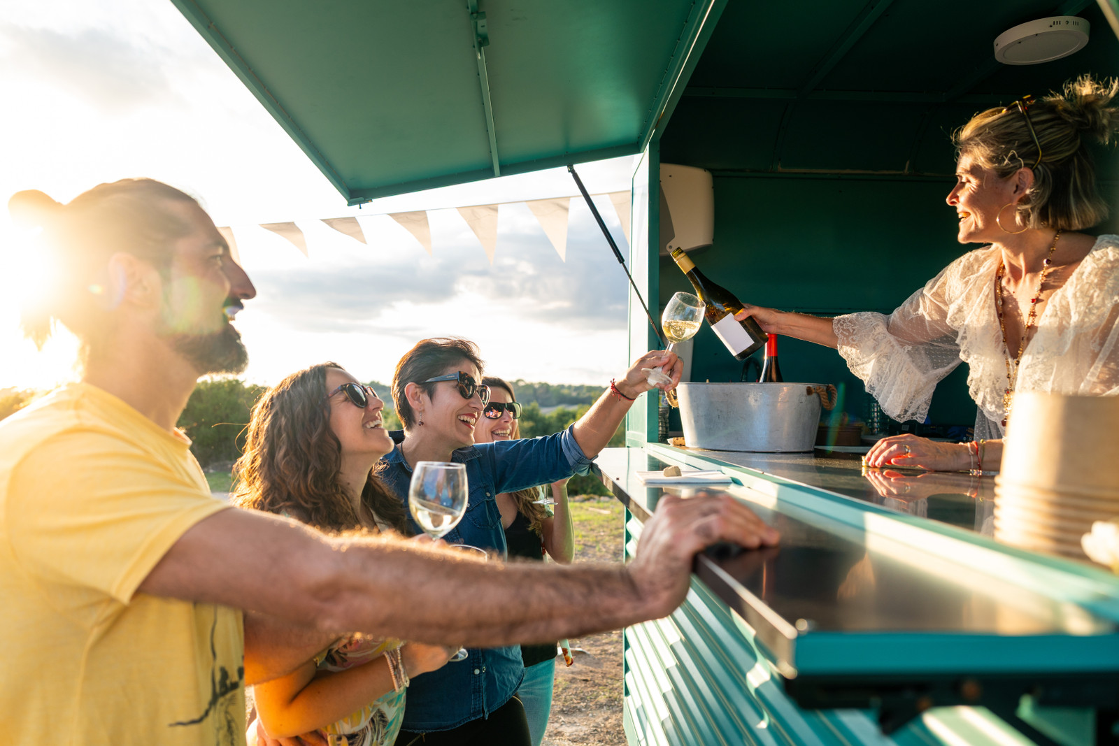 A food truck vendor pours drinks during a busy outdoor event.