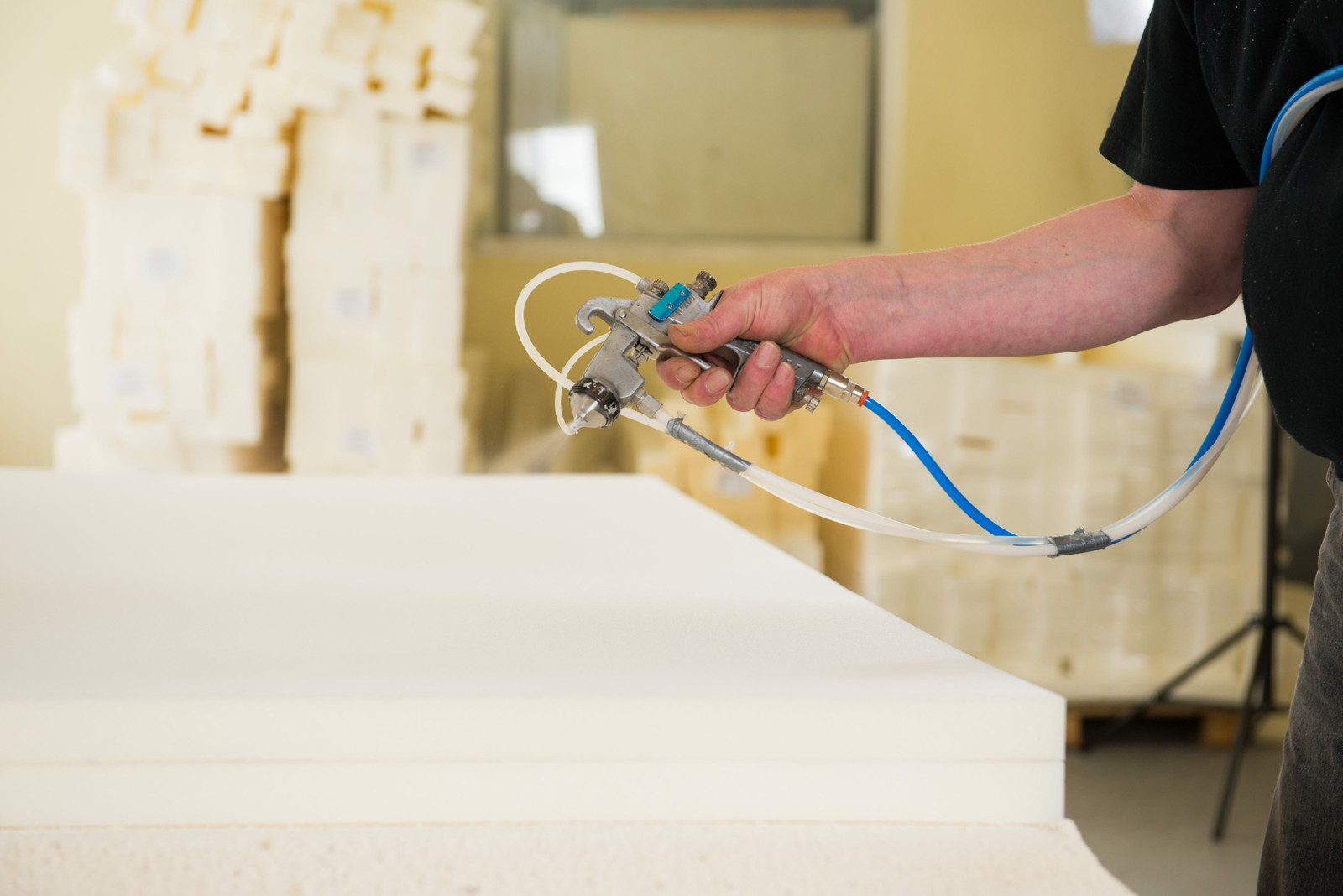 A worker uses spray adhesive to build furniture.