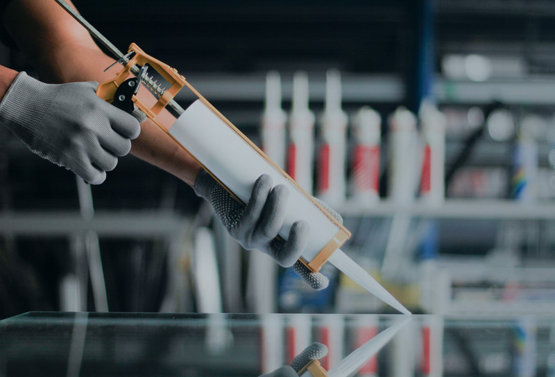 Person applying adhesive using a dispensing gun