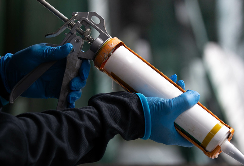 Person using dispensing gun to apply adhesive