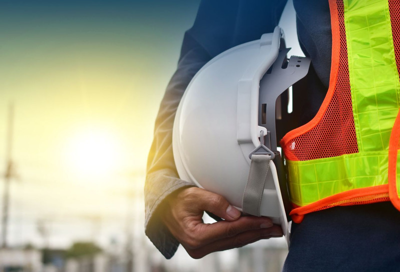 Person with safety vest standing with hard hat