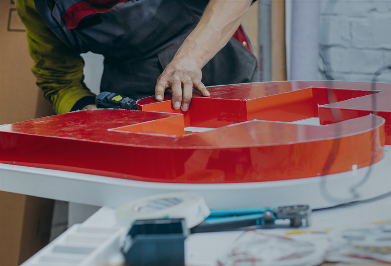 Person constructing a letter sign using a drill and fasteners
