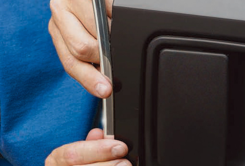 Close up of man applying metal trim to vehicle door