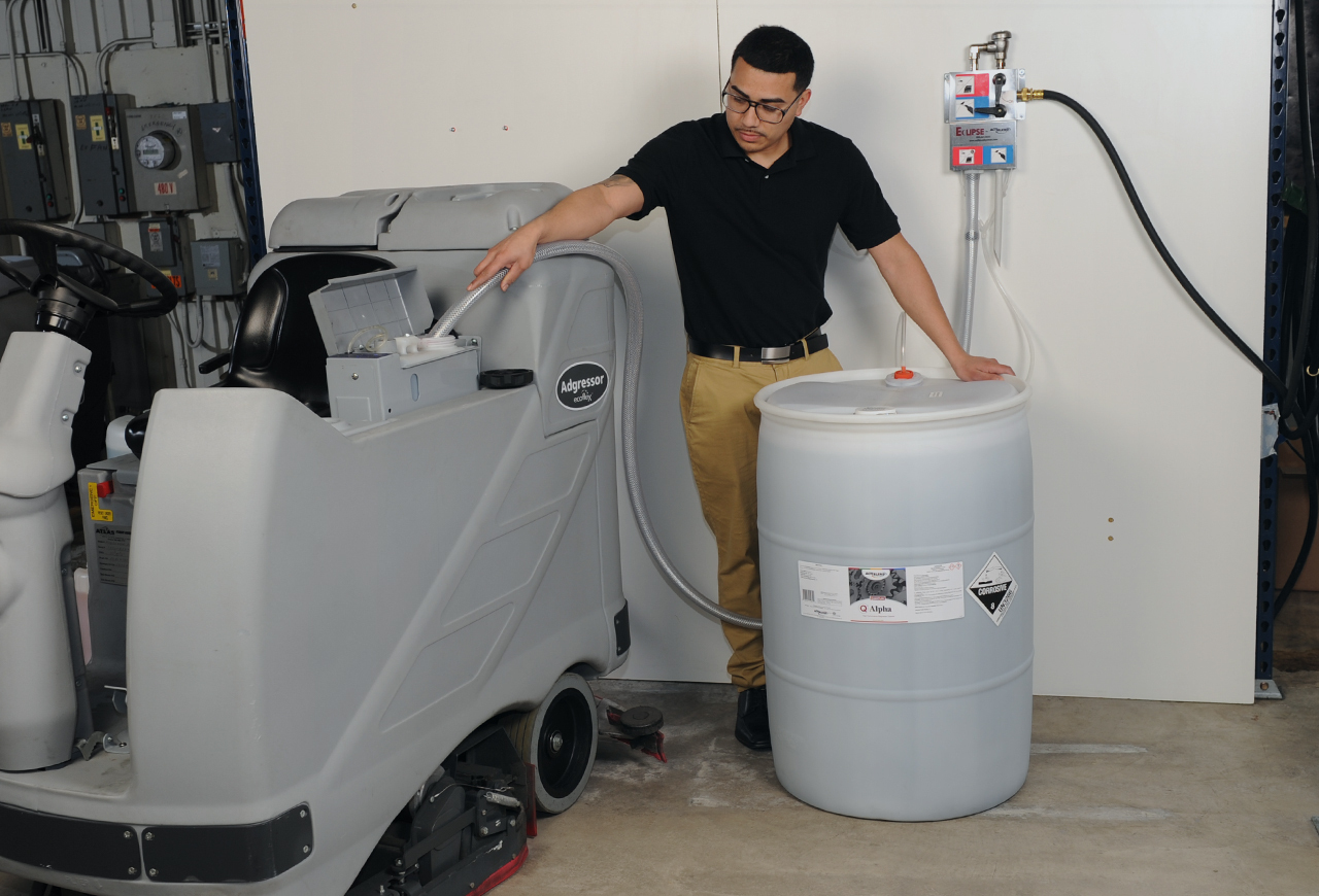 Person using a dispensing unit to add Sigma cleaner to cleaning machine