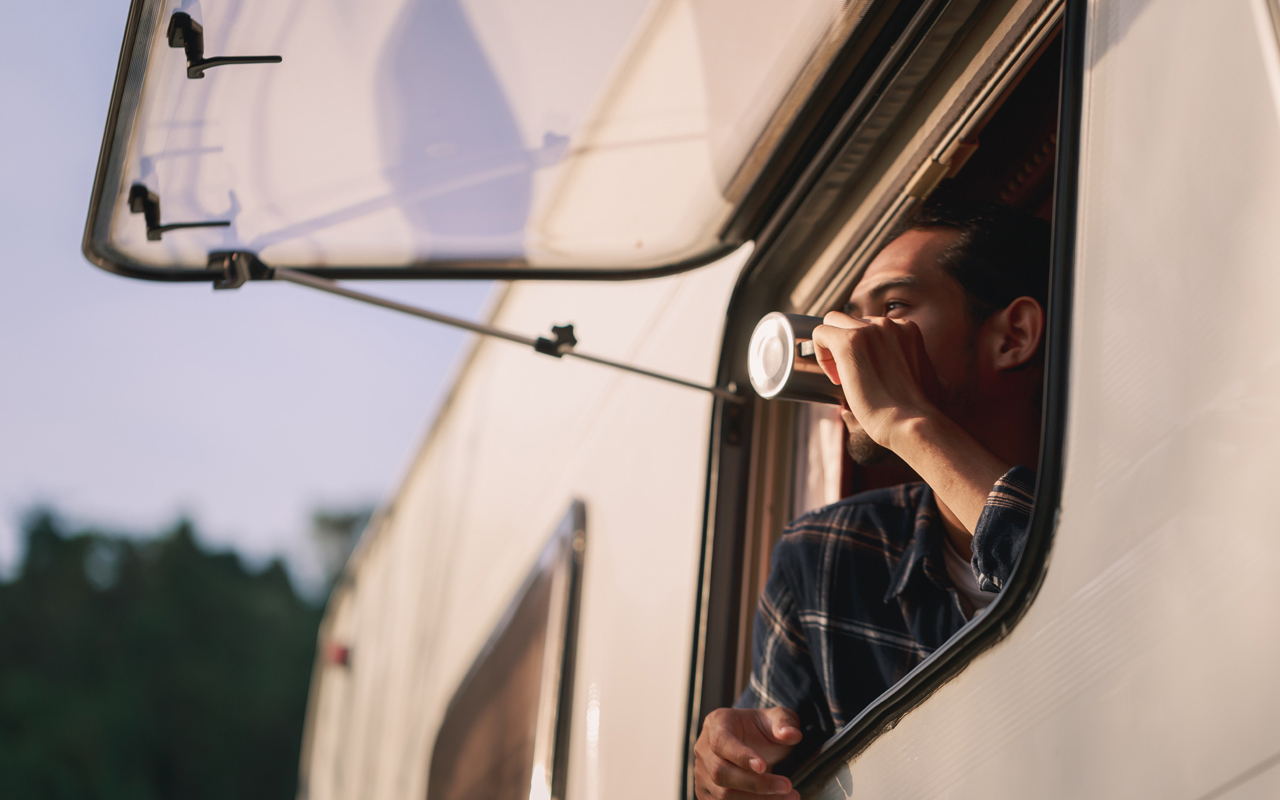 Man looking out RV window drinking coffee showing the trim around window
