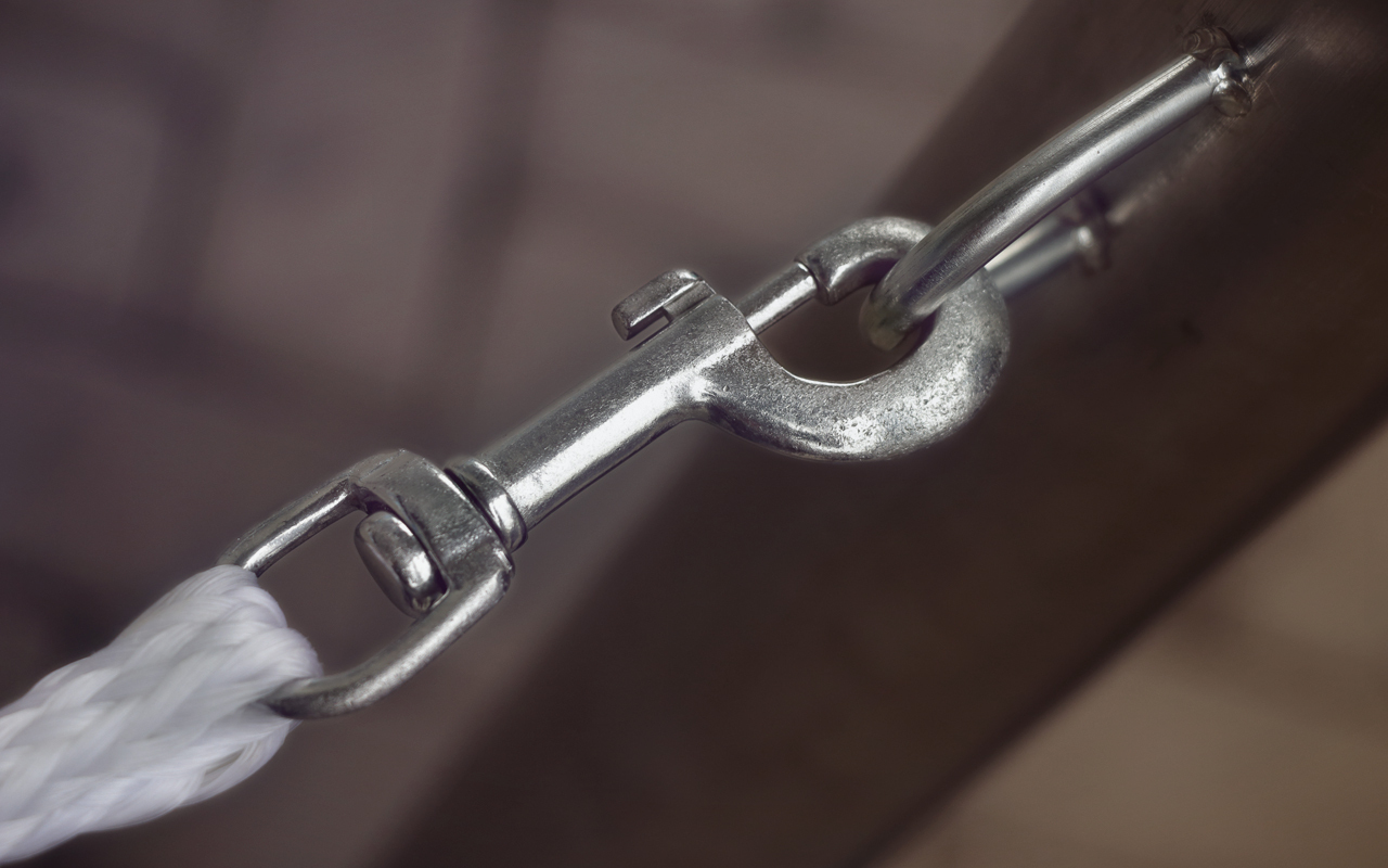 Snap latch holding rope to metal loop on wall
