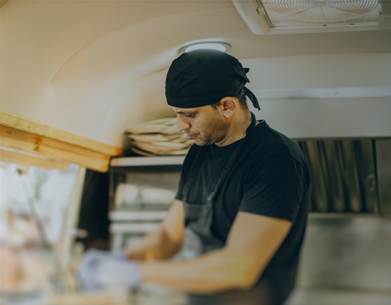Chef cooking in a food truck with vent overhead