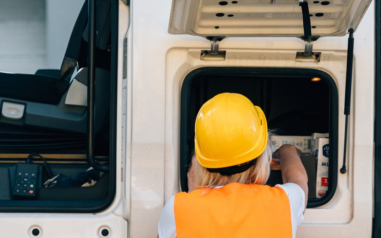 Woman getting items out of compartment on work truck showing the rubber trim around opening