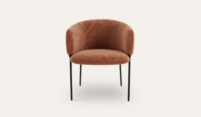 Mila dining chair with soft upholstery, curved wraparound backrest and slim black metal legs, designed for modern dining spaces.