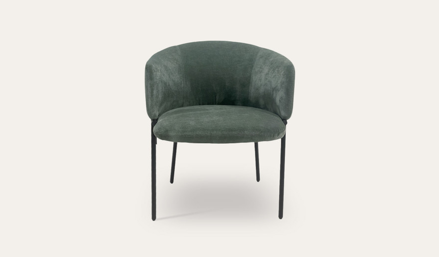 Mila dining chair with soft upholstery, curved wraparound backrest and slim black metal legs, designed for modern dining spaces.