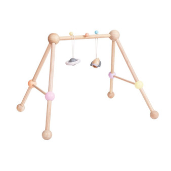 The Image of The Plan Toys Play Gym in A Touch of Pastel is an intergalactic themed baby gym made with solid natural wood with pastel painted details and a hanging rocket and planet to entertain your baby.