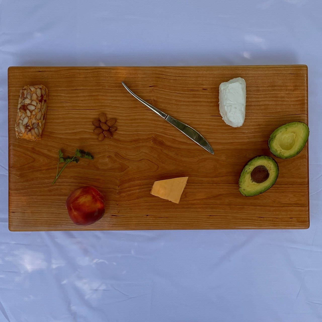https://cdn11.bigcommerce.com/s-1vey7r6116/images/stencil/1280x1280/products/136/522/cherry-serving-board-by-Treeboard-cheese-hands-avocado-from-above__34244.1693096774.jpg?c=1