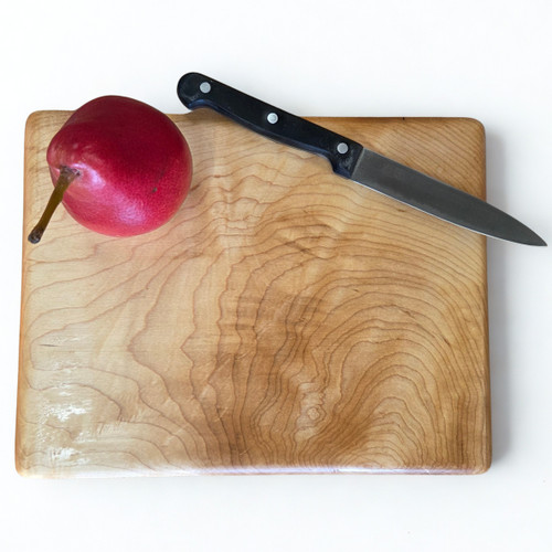 Small hard maple chopping board by Treeboard with knife and red pear.