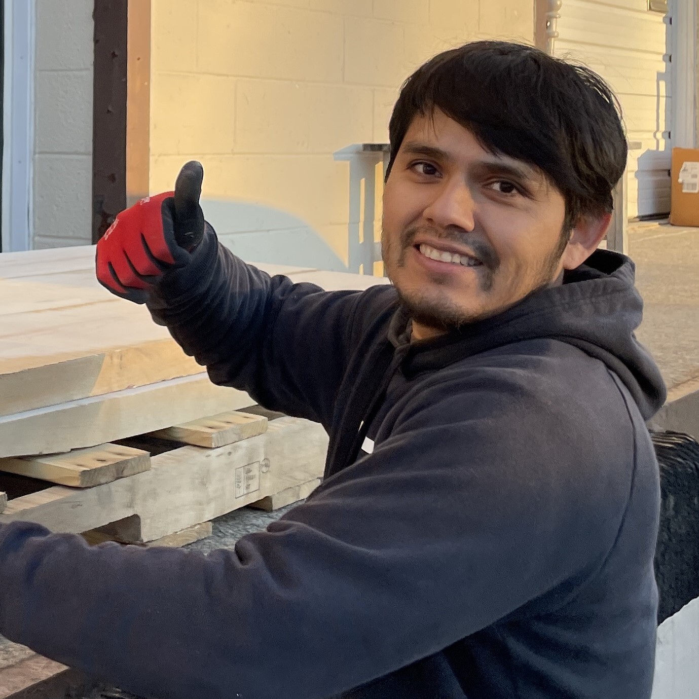 Alberto with gloves showing a thumbs up sign. Treeboard's woodworker.