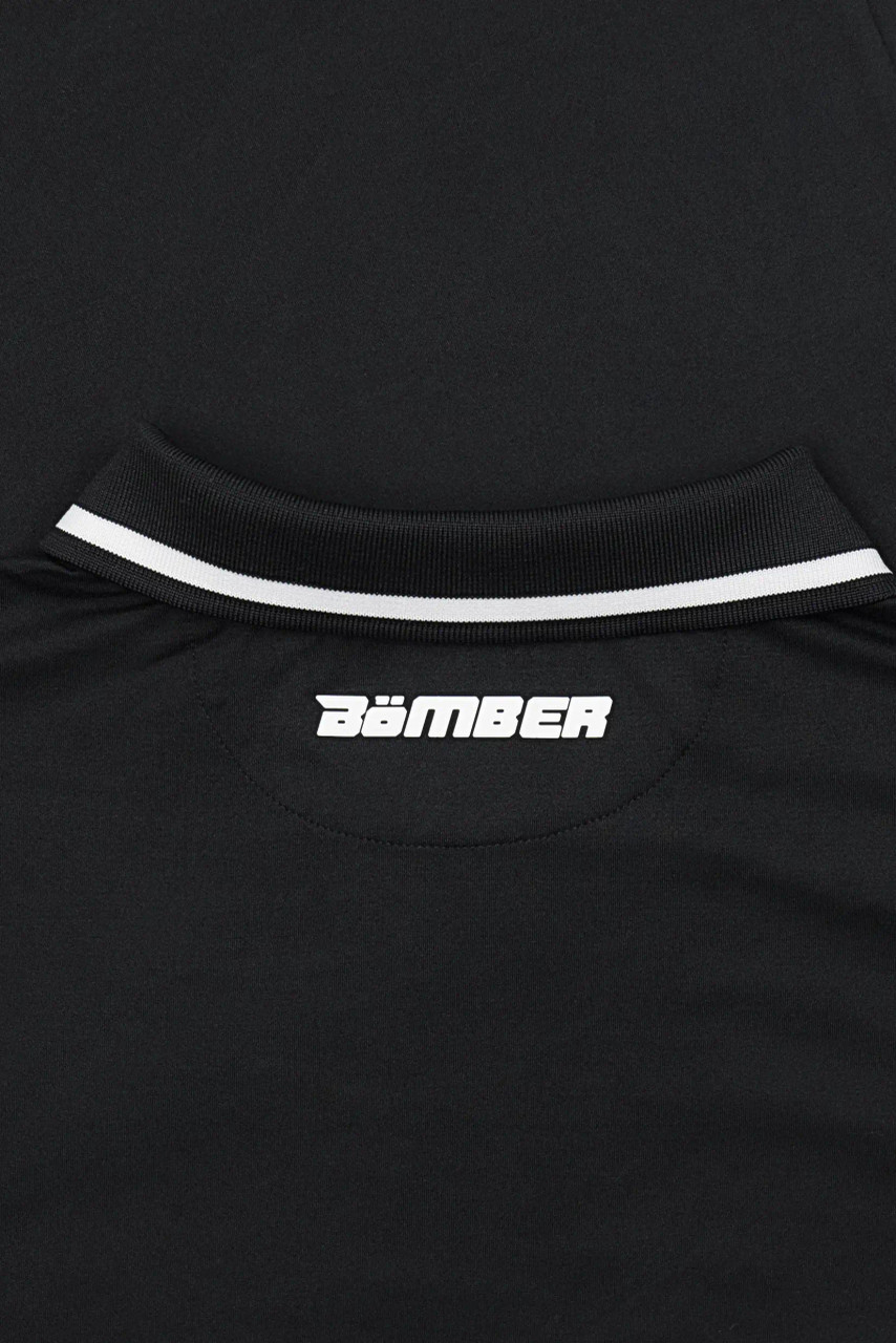 Acropolis Polo, black performance polo with silicone Bomber hip logo, close-up view