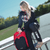 Photo of a woman using the red Combat Corner Vital 30 Training Backpack on her college campus in between her classes.