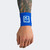 A model's relaxed hand and tattooed arm wearing a blue Combat Corner Lightweight Sublimated Scoring Wristband, isolated on a plain light gray background.