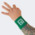 A model's tattooed arm pointing upward while wearing a green Combat Corner Lightweight Sublimated Scoring Wristband, isolated on a light gray background.