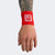 A model's relaxed hand and tattooed arm wearing a red Combat Corner Lightweight Sublimated Scoring Wristband, isolated on a plain light gray background.
