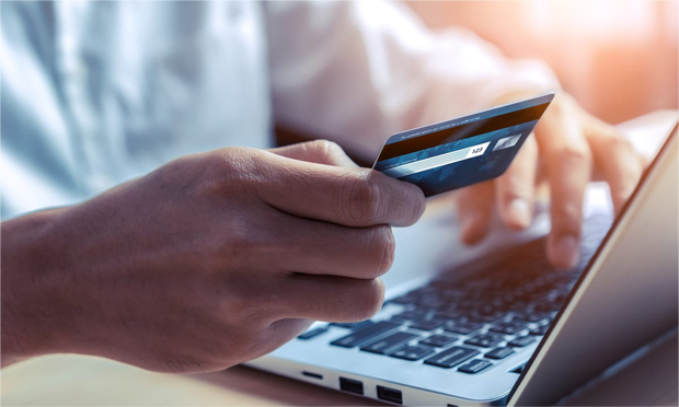 Typing credit card information into a laptop.