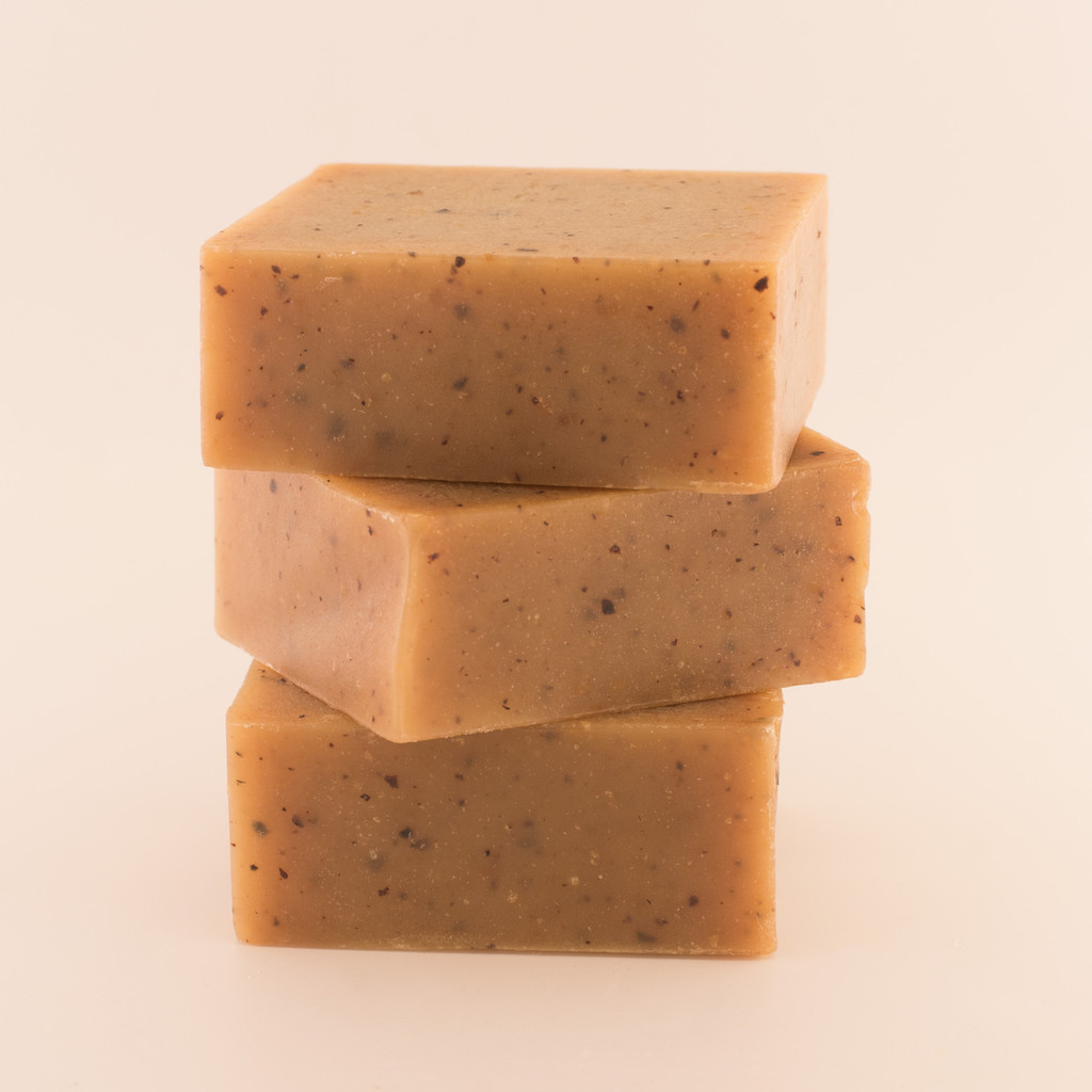 Three unwrapped bars of discounted Sweet Almond Honey goat milk soap, stacked.