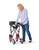 A smiling woman standing and easily folding the red Comodita Tipo Petite All-Terrain Rollator by pulling upward on the seat handle, demonstrating its collapsible frame against a white background